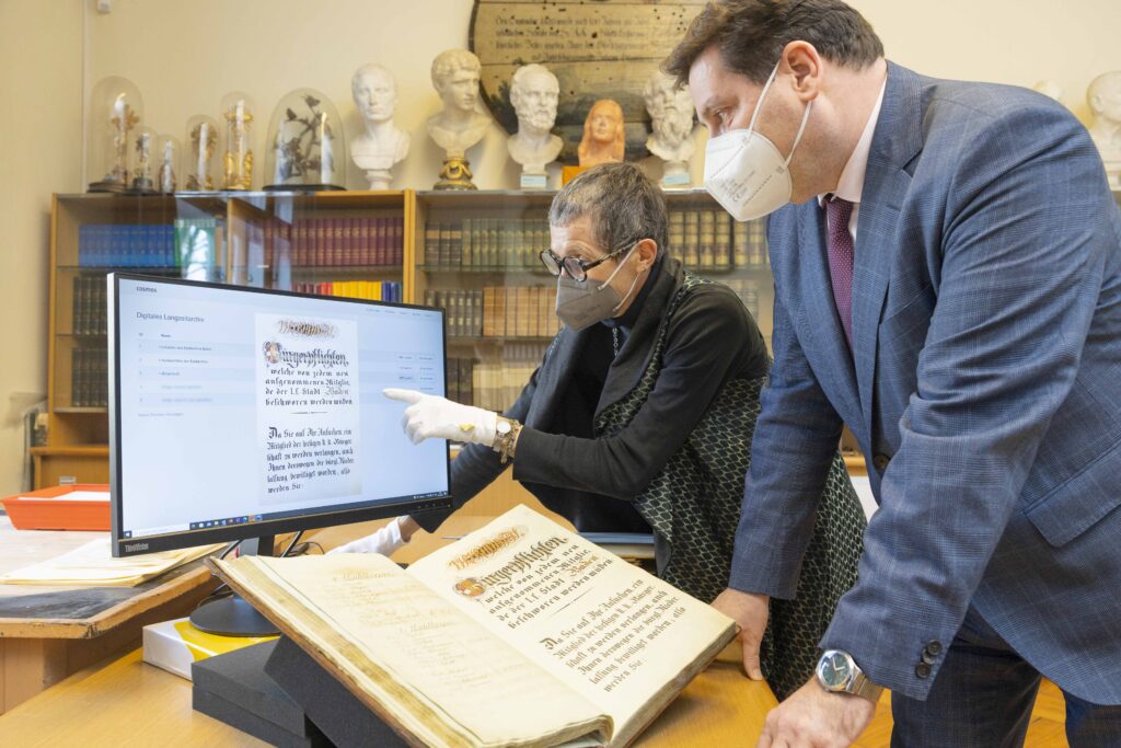 Zwei Personen schauen auf einem Bildschirm.